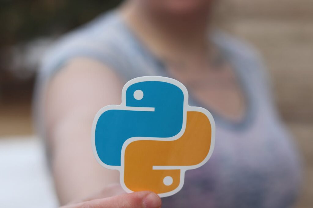 Crafting Captivating Headlines: Your awesome post title goes here Person holding Python logo sticker with blurred background, highlighting programming focus.