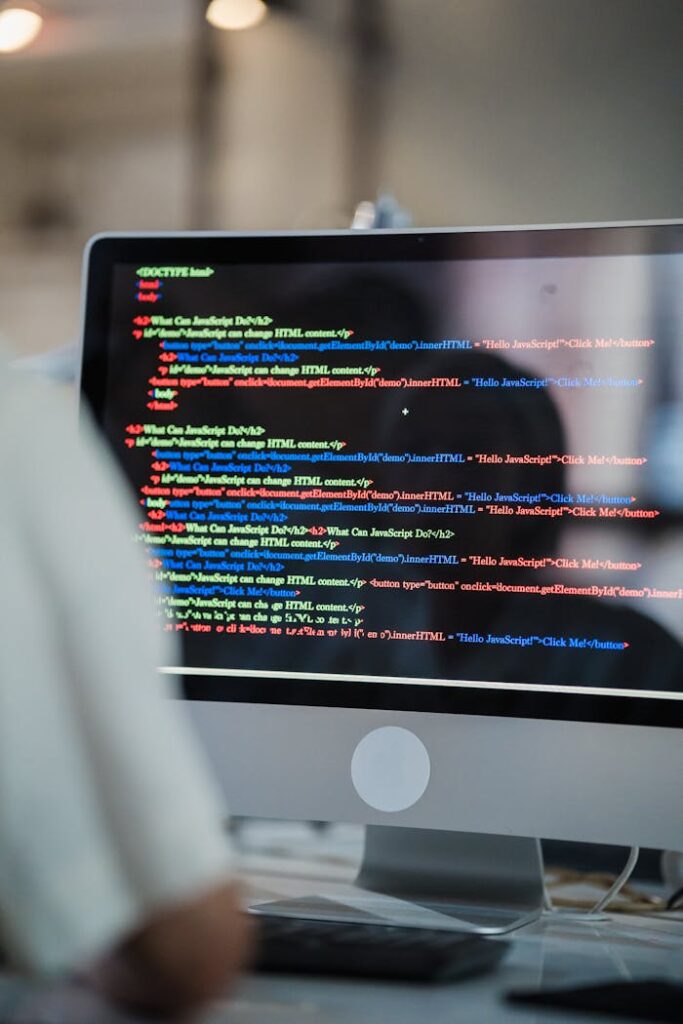The Art of Drawing Readers In: Your attractive post title goes here A close-up of a computer screen displaying colorful coding script in an office environment.